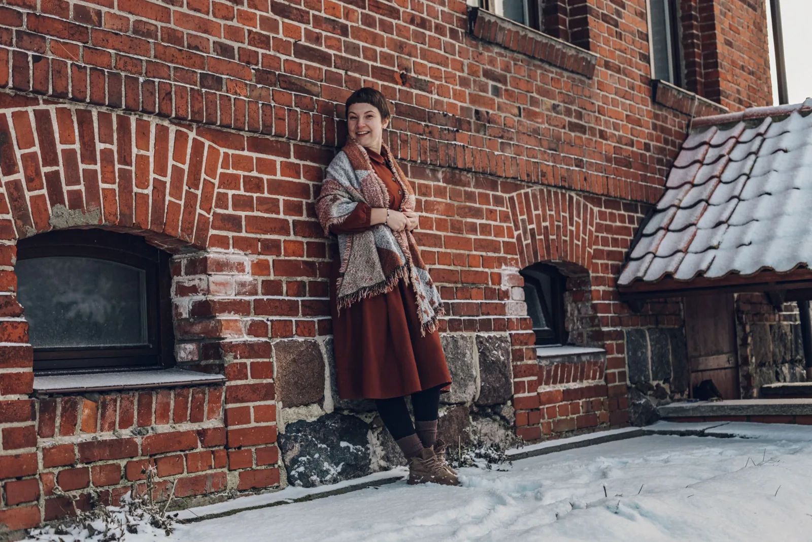 Кирпичная стена, снег и шаль поверх красного платья. Фото: Настя Шафранова