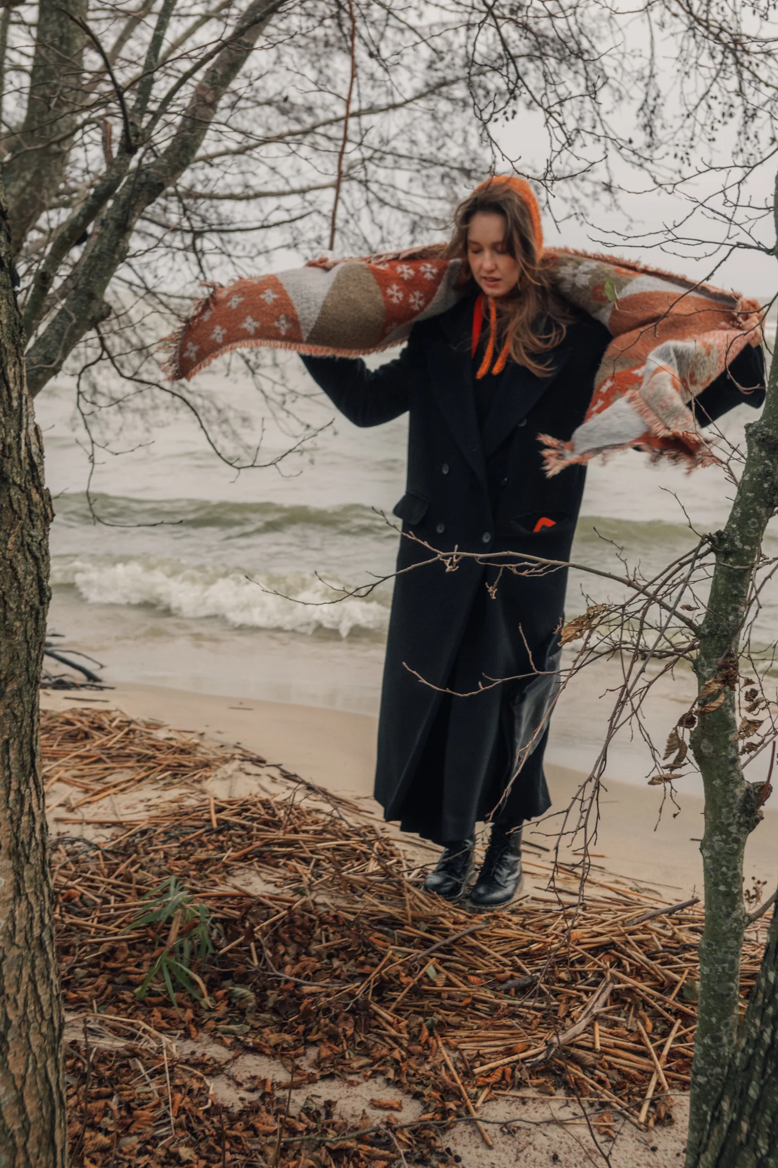 Раскрыла шарф на ветру, как крылья, и стоит на куче сухих стеблей