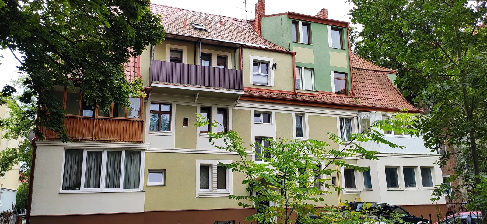 Старый дом в Амалиенау: черепичная крыша, мансардные окна, разноцветные фасады и деревья перед ними. Фото: Настя Шафранова