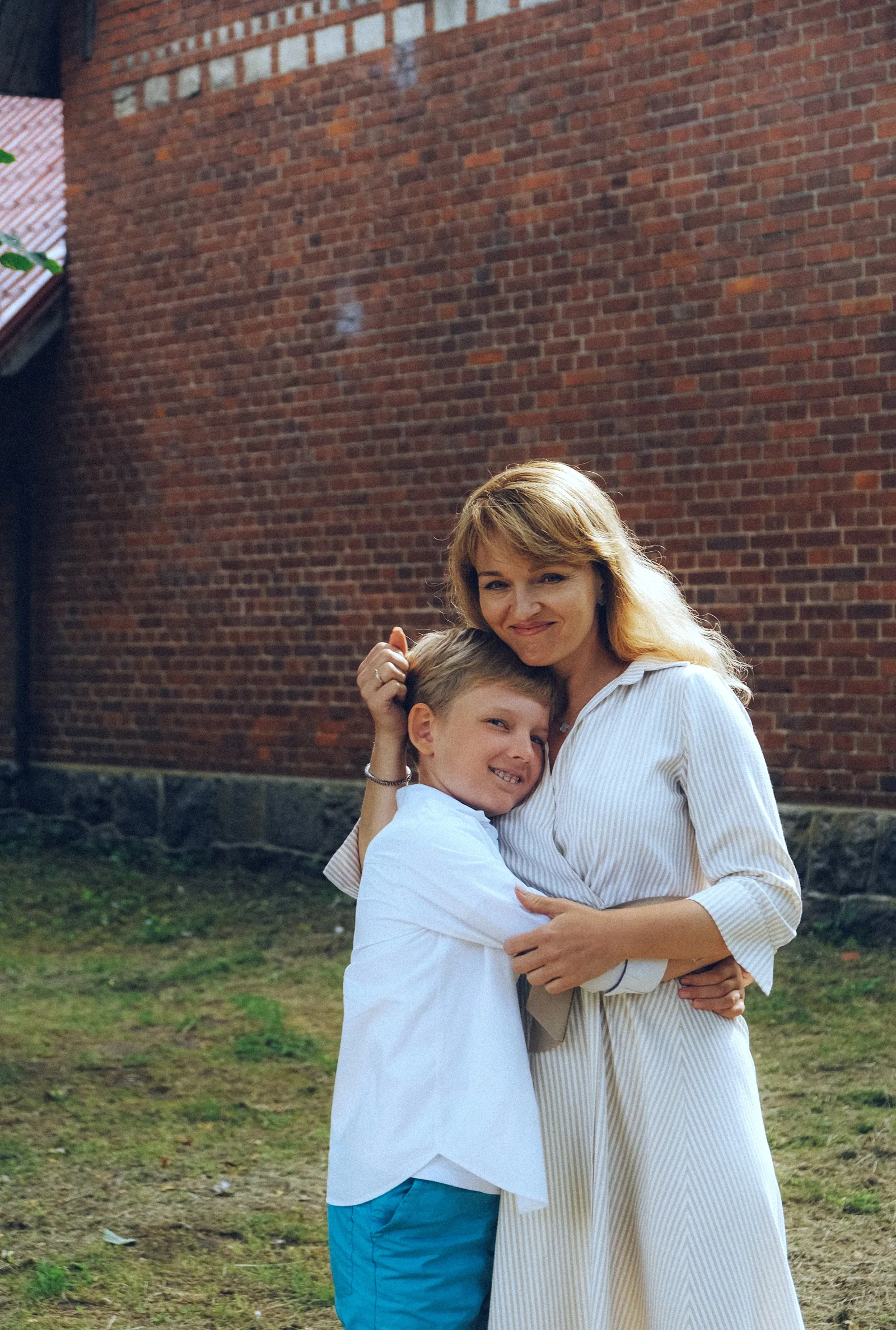 Мальчик обнял женщину за шею и прижался к ней щекой. Она обхватила его обеими руками и улыбается