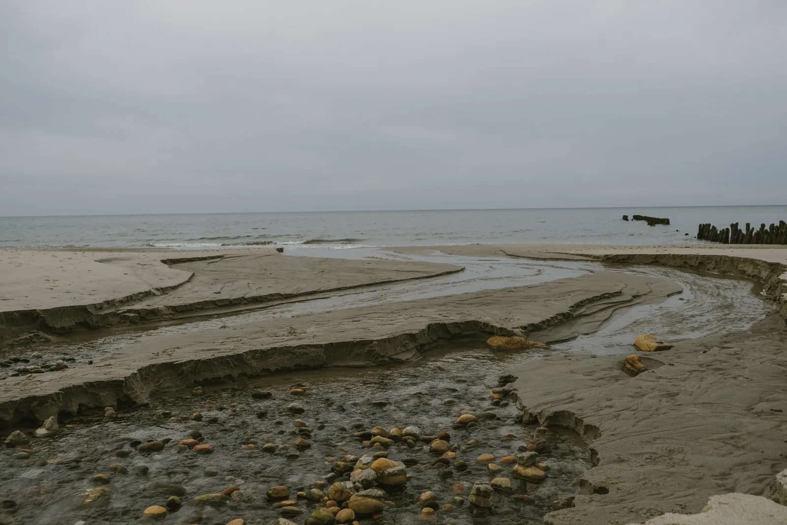 Ручей размывает песок и выходит к морю, в русле лежат круглые камни: здесь, на границе пресной и солёной воды, галька самая гладкая. Фото: Настя Шафранова