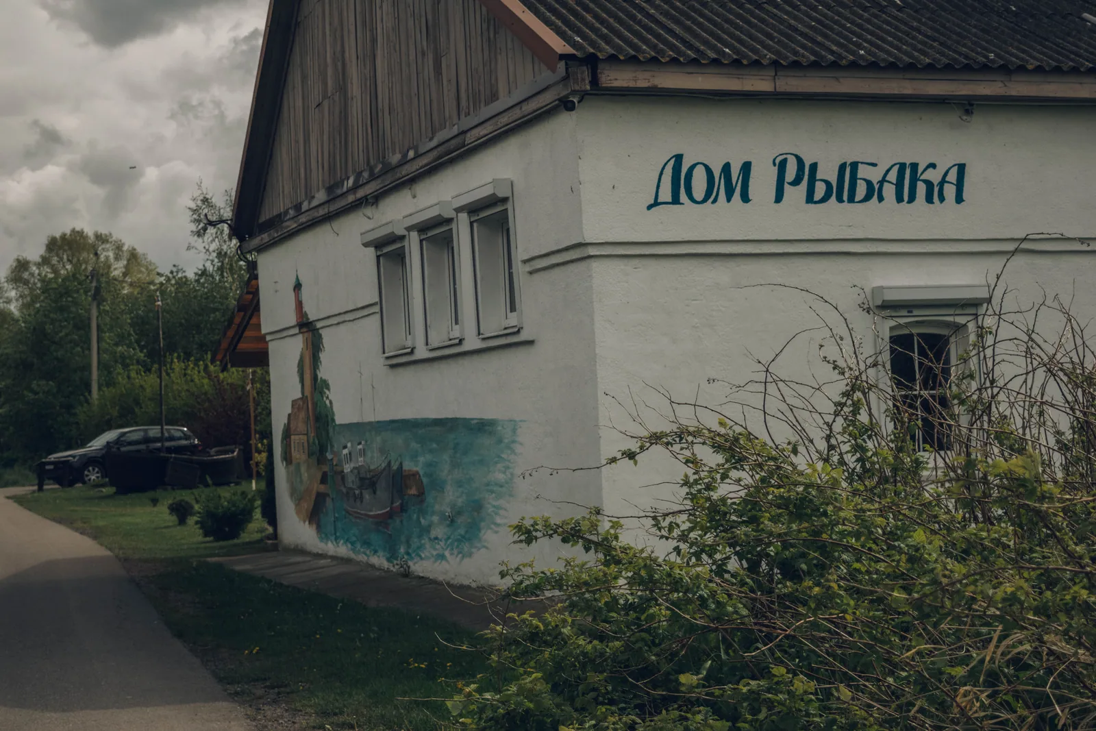 Белёный дом с надписью «Дом рыбака», на стене нарисованы вода, лодки и маяк